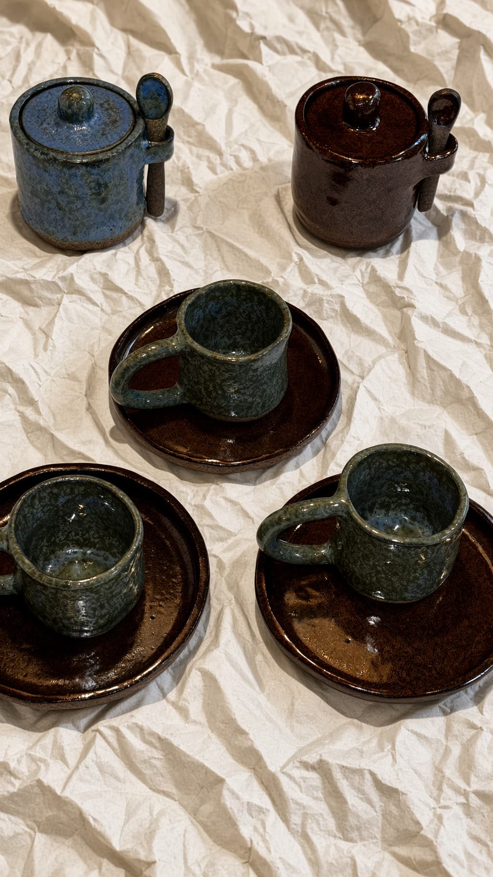 Três xícaras verdes com pires chocolate e dois açucareiros com colher