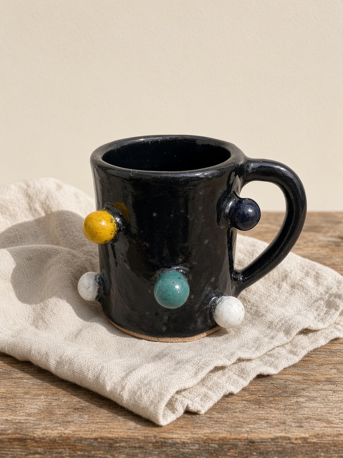 Caneca preta de cerâmica com bolinhas amarela, branca, verde e azul